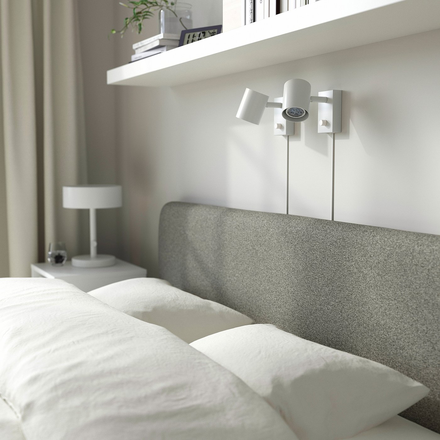 Modern grey bed with adjustable light, neat white bedding, minimalist bedside table, books & plant on shelf.