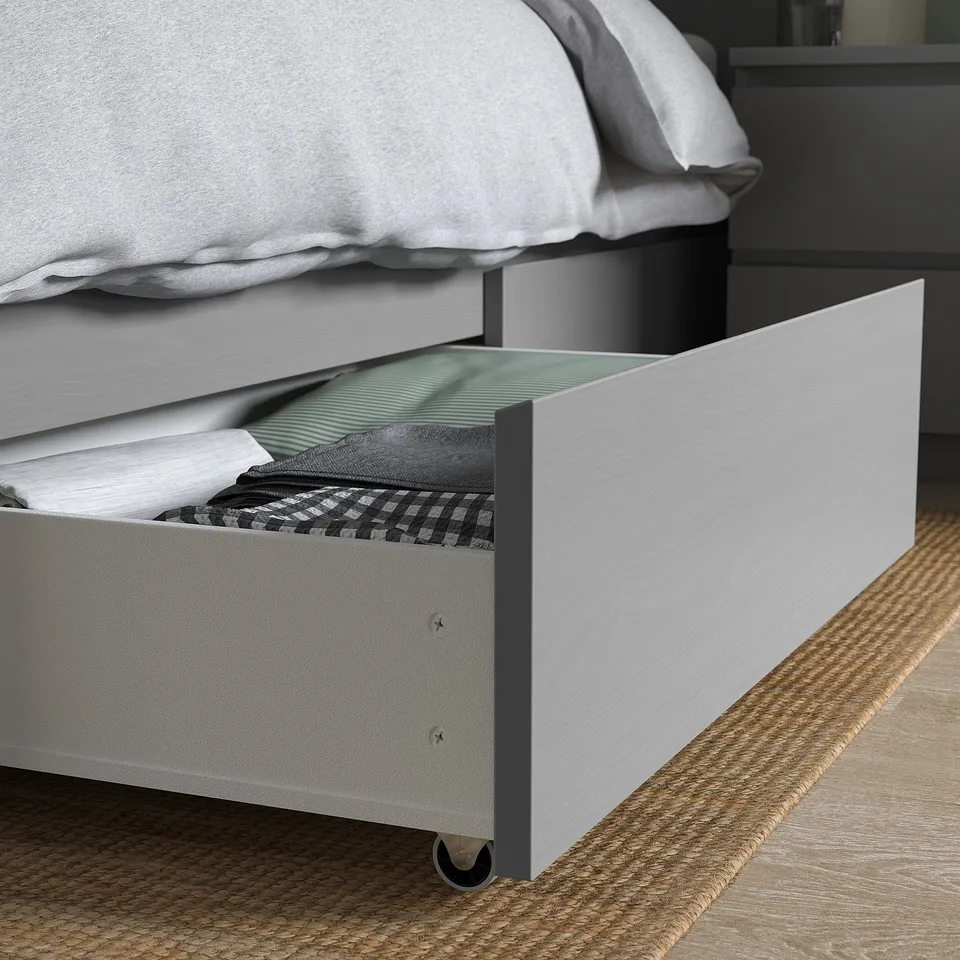 Bedside storage: open drawer under bed shows folded clothes, demonstrating practical organisation.