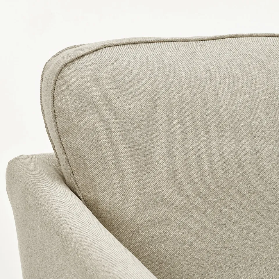Sofa corner detail: sleek, beige upholstery. Neat piping edges. Quality craftsmanship.
