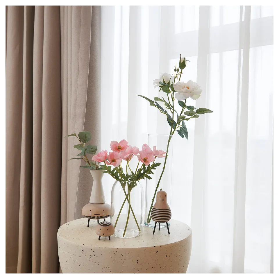 Three colourful vases on white table by window.