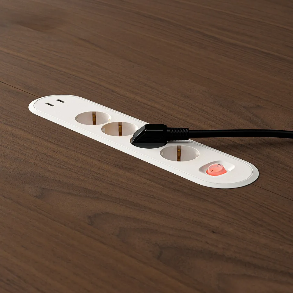 Circular power outlet on wooden table with built-in cable management tray.