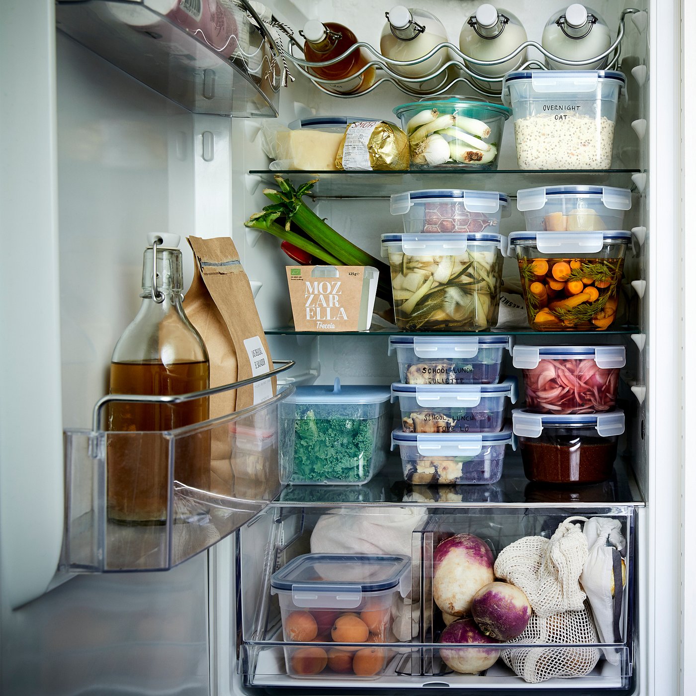 Organised refrigerator with clear containers for leftovers and vegetables.