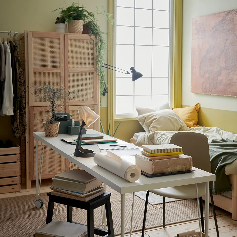 White KRILLE desk with black legs on wheels, yellow room. Modern, mobile, minimalist design.