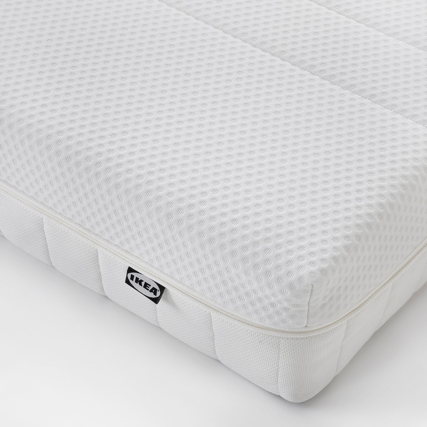Close-up of IKEA mattress, new, white, smooth texture, clean surface, marked IKEA.
