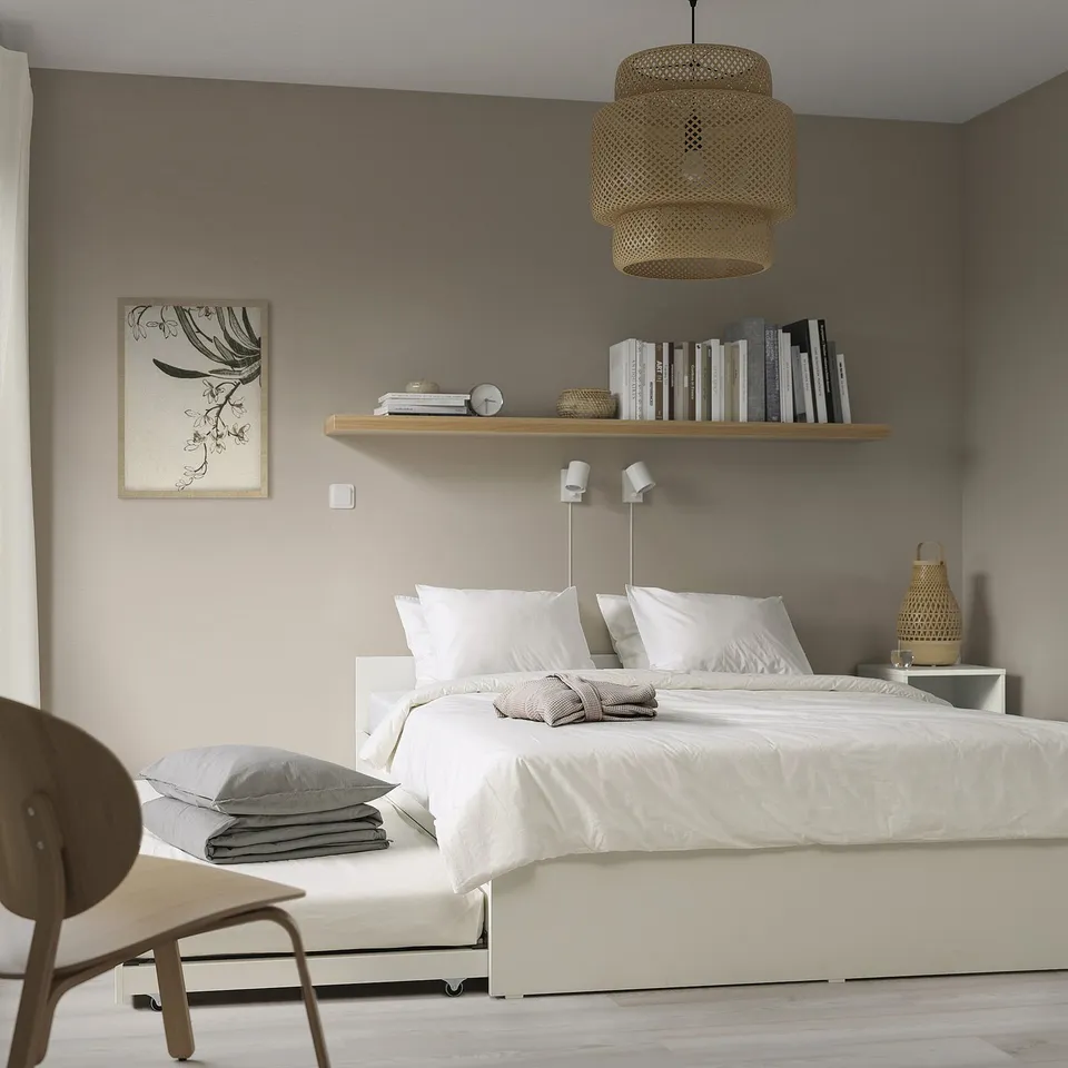 Modern bedroom with VIHALS white bed, trundle, bookshelf, pendant lamp, and chair.