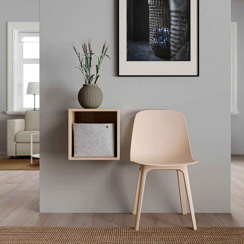 Modern interior with light-colored wooden floor, beige chair, grey cabinet, grey rug, white lamp, and wall art.