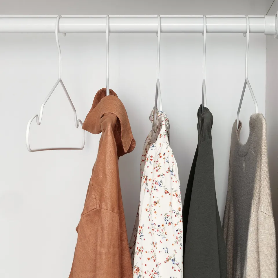 Four colourful clothes hang on thin, non-slip STAJLIG hangers in wardrobe.