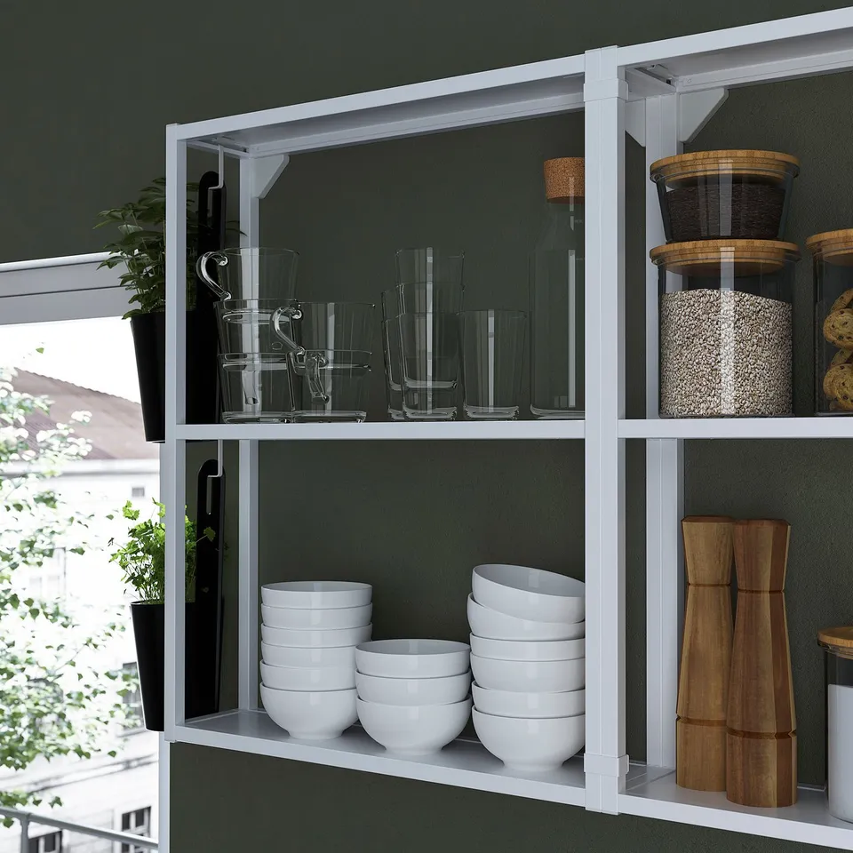 White shelves store bowls, glasses, and containers. Green wall background. Perfect for kitchen or bathroom.