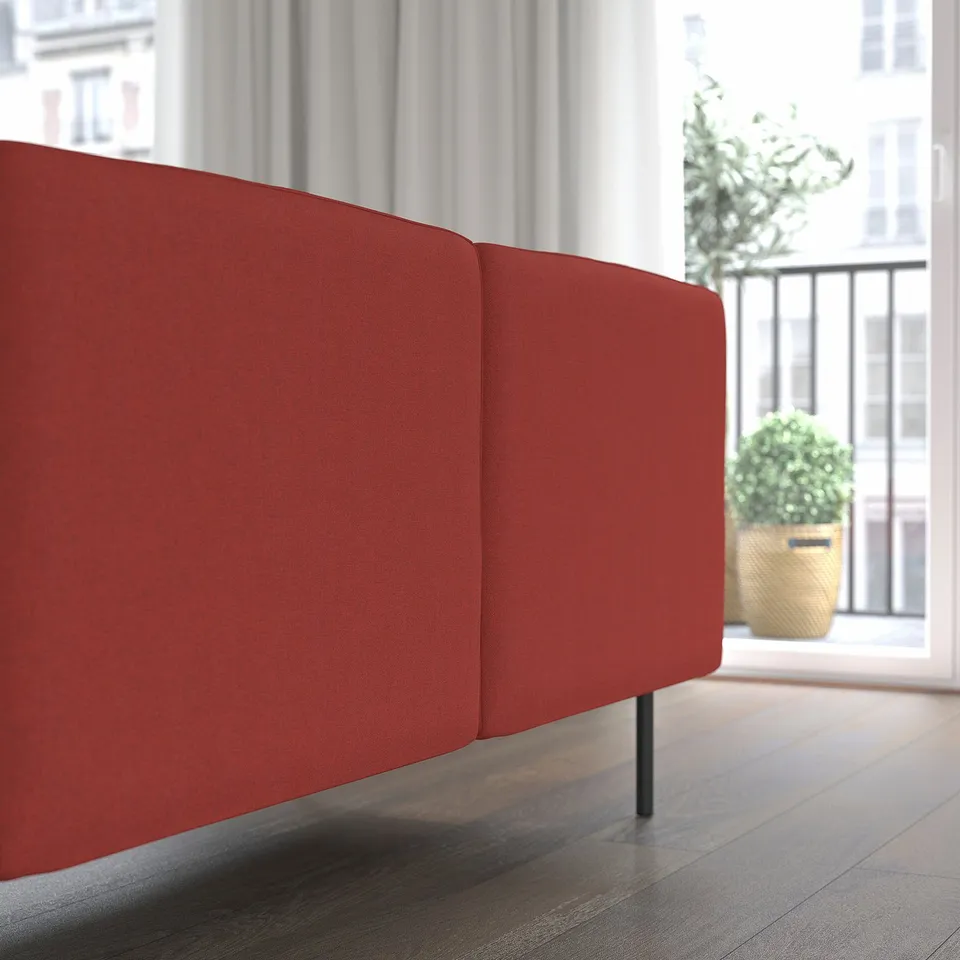 A modern, vibrant red modular sofa section against a large window, showcasing its sleek, easy-to-clean fabric and comfortable cushions.