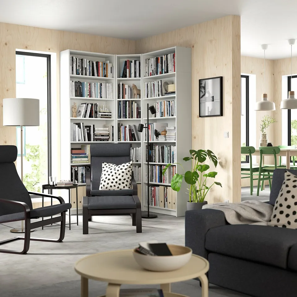 Modern living room with white BILLY bookcases, grey furniture, polka dot pillows, and large windows.