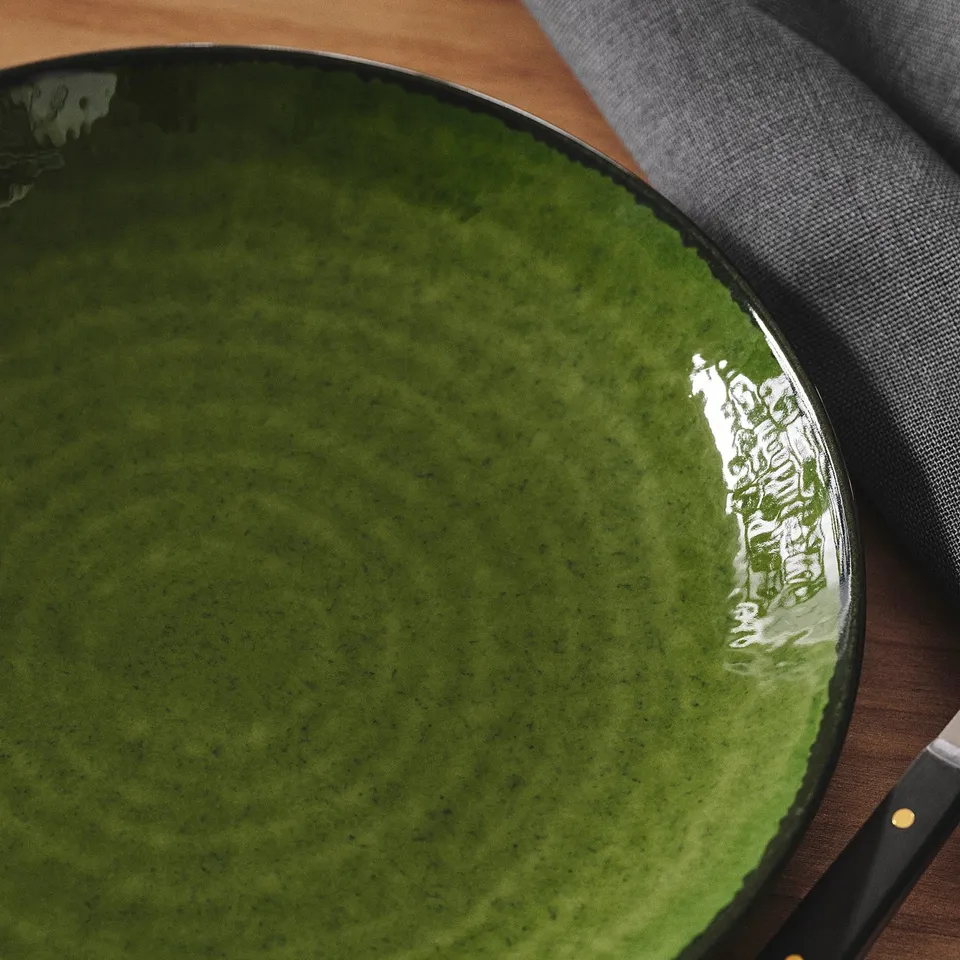 A high-quality green stoneware dish with glossy finish, resting on a table.