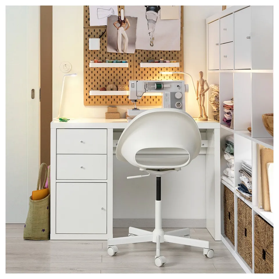 Well-organized craft room with white KALLAX storage, pegboard, sewing machine, and adjustable chair.