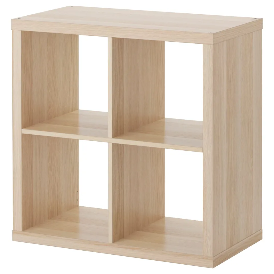 An empty wooden KALLAX bookshelf in white, featuring four open compartments, standing against a white background.