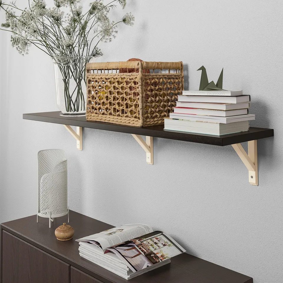 Dark shelf with gold brackets, vase, books. Below, cabinet with lamp.