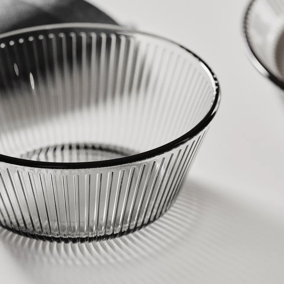 Black and white close-up of a textured glass bowl, showcasing its sleek design and reflecting light, emphasising its durability and sophistication.