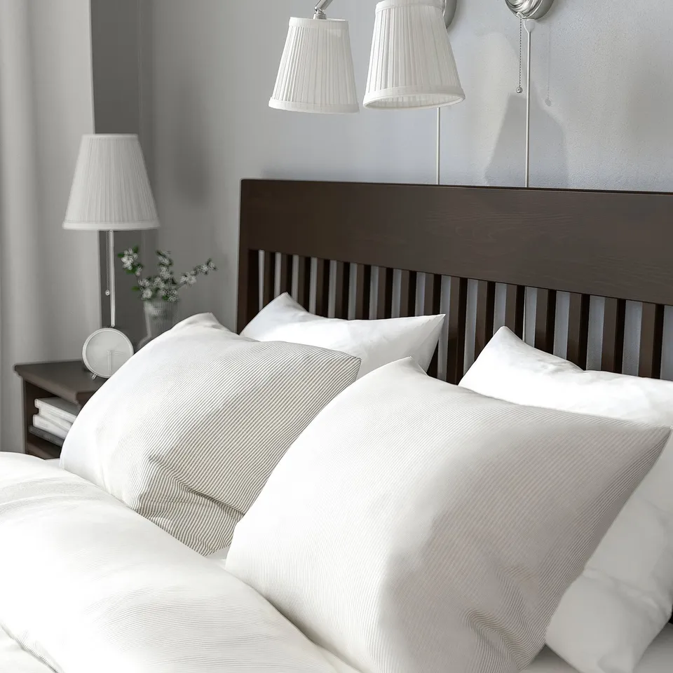 Dark wooden bed with white sheets, pillows, and two lamps.