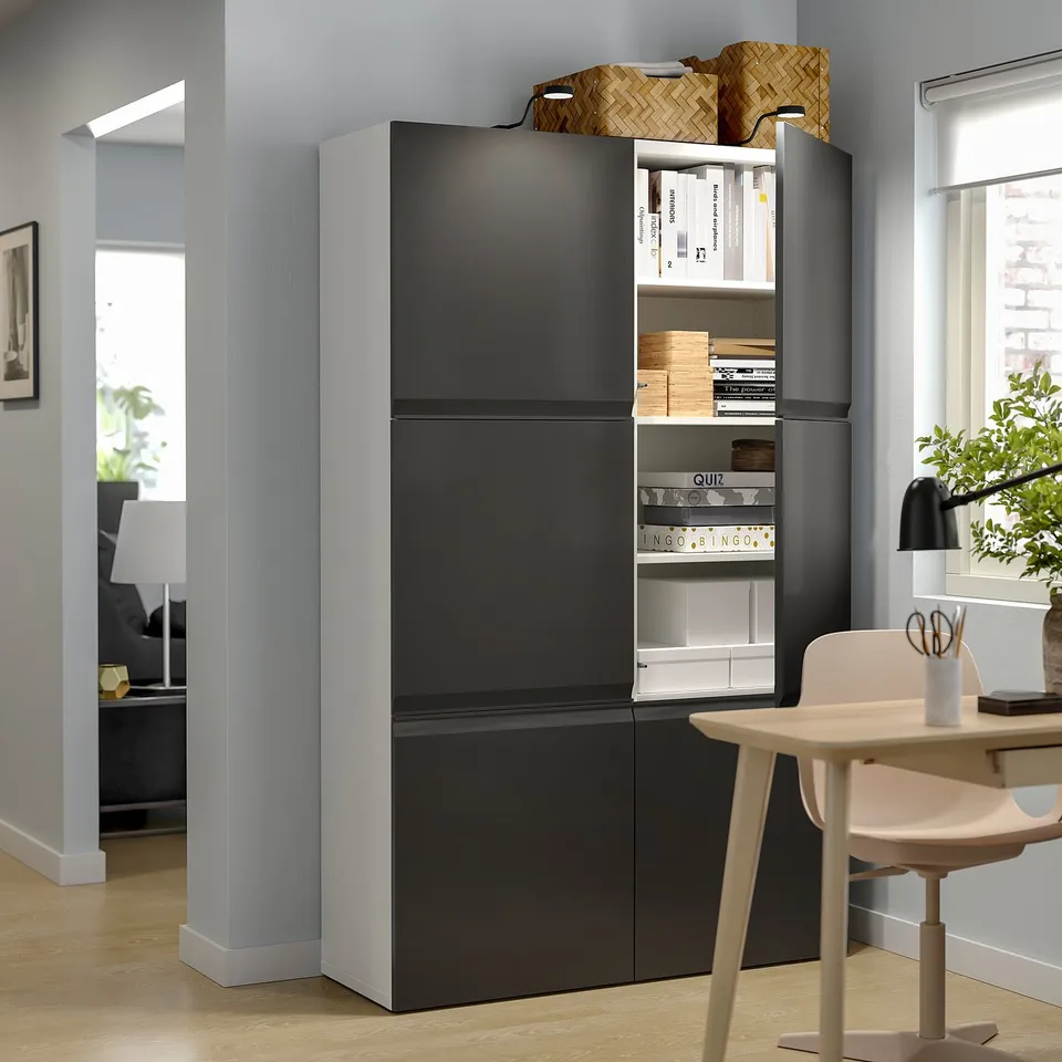 Modern living room a tall, black BESTÅ storage unit with adjustable shelves and doors, housing books and decorative items.