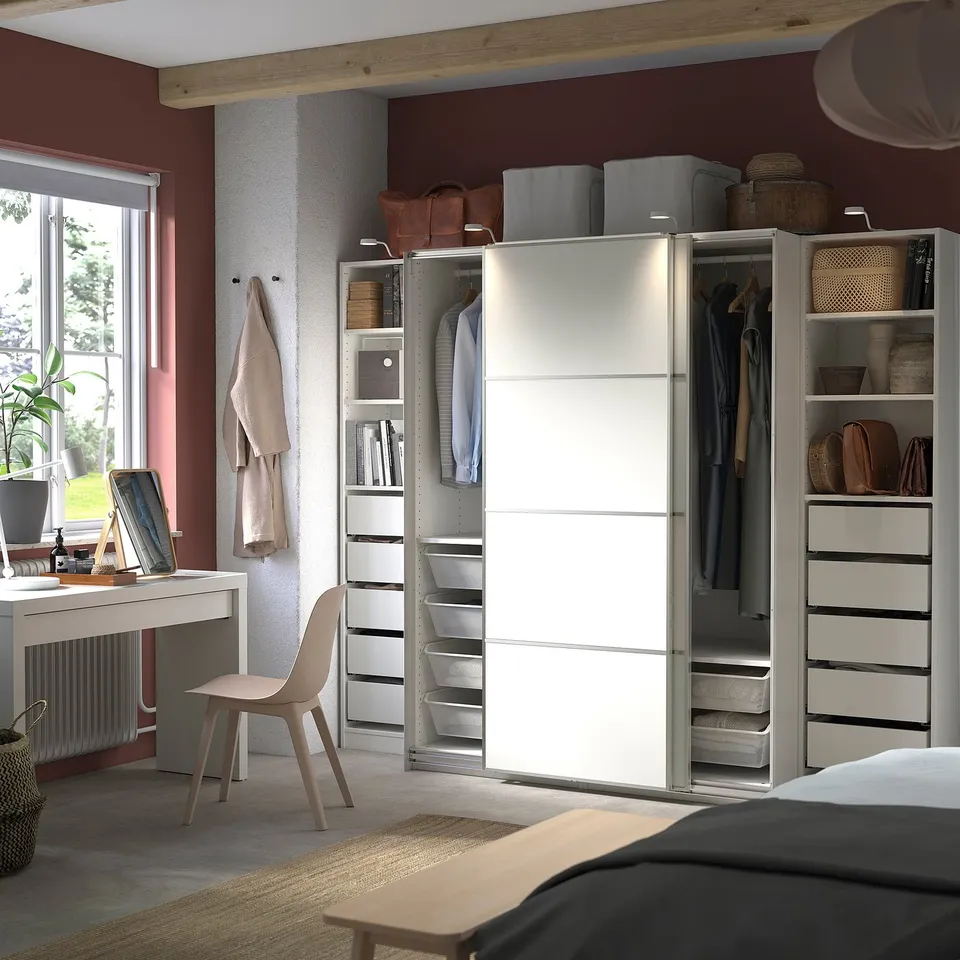 Modern bedroom with white PAX wardrobe, wooden desk, chair, and hanging towels.