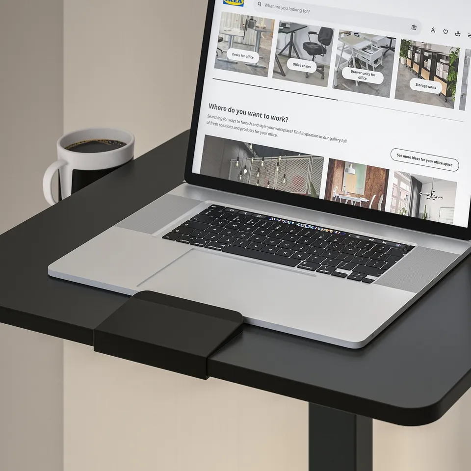 Laptop on adjustable table, beside coffee cup.