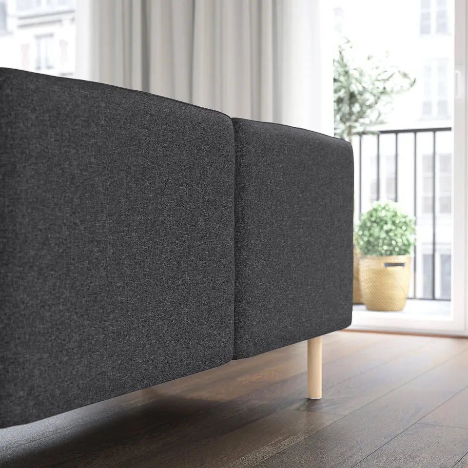 Dark grey modular sofa with wooden legs in modern room, offering adaptable comfort.