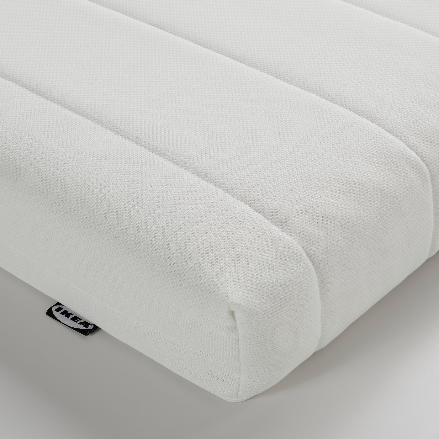 White foam mattress corner, firm, with ikea tag, neatly folded.