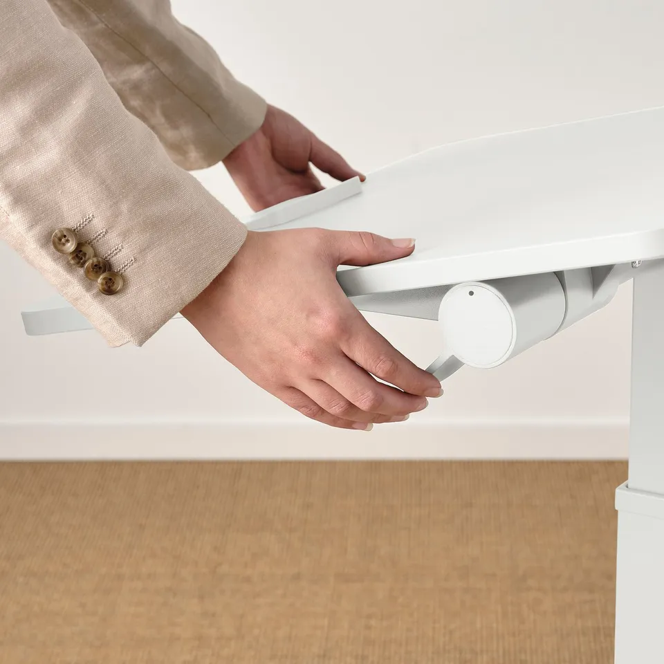 Person adjusting height of MITTZON laptop table, showcasing its gas spring mechanism for standing or sitting use.