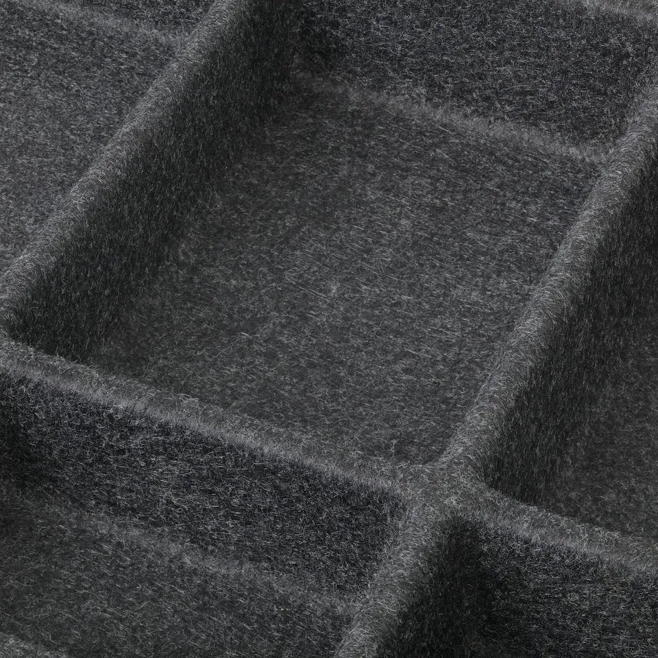 Close-up of textured fabric, dark grey with subtle patterns, folded neatly.