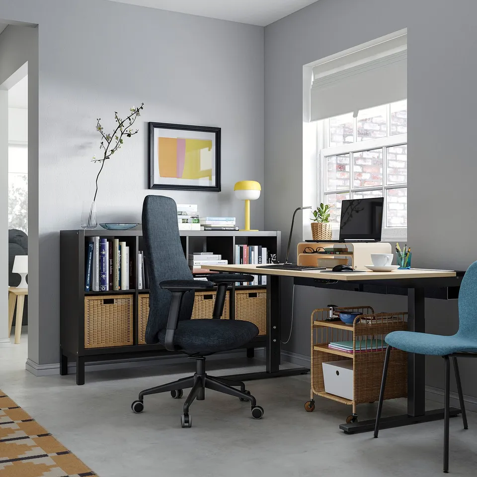 Modern home office with a grey chair, wooden desk, bookshelf, and large window. Stylish and organised with natural elements.