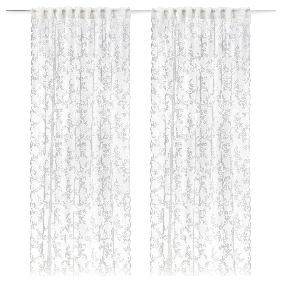 Pair of sheer white lace curtains with floral pattern, curved edges, and heading tape for easy hanging.