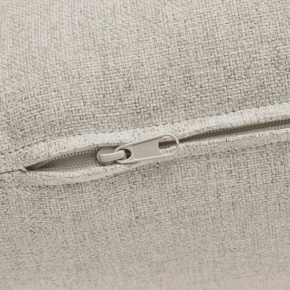 A zip on a beige fabric couch section, showing quality design detail.