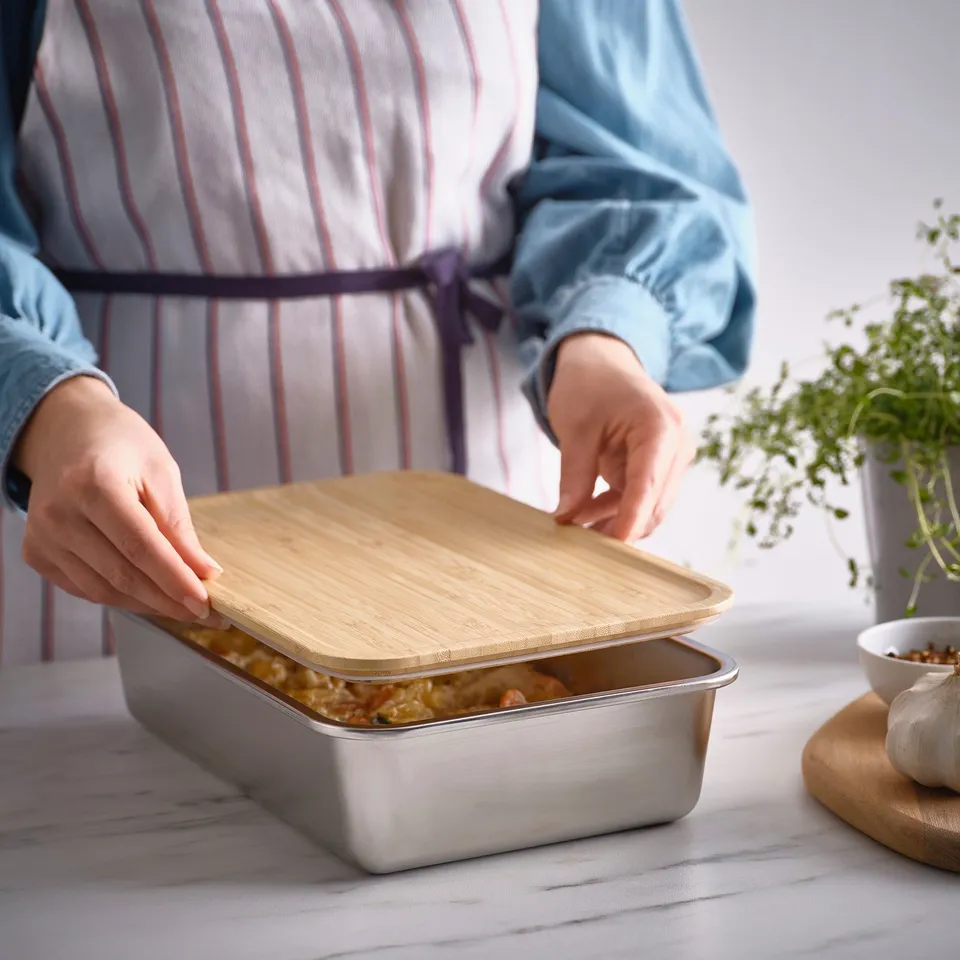 Person places lid on stainless steel food container, storing leftovers for later use, promoting food waste reduction.