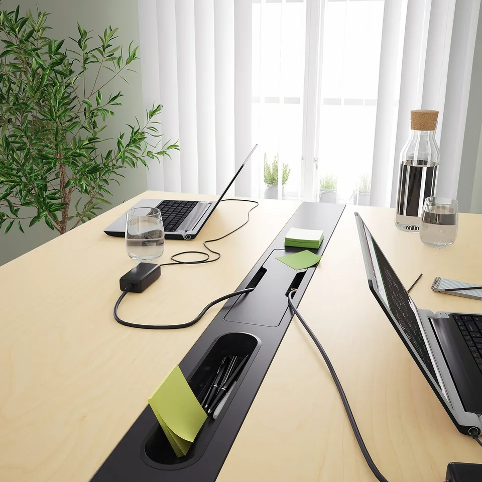 Modern conference table with built-in power outlets and cable management, suited for sitting or standing, with a footrest for added support.
