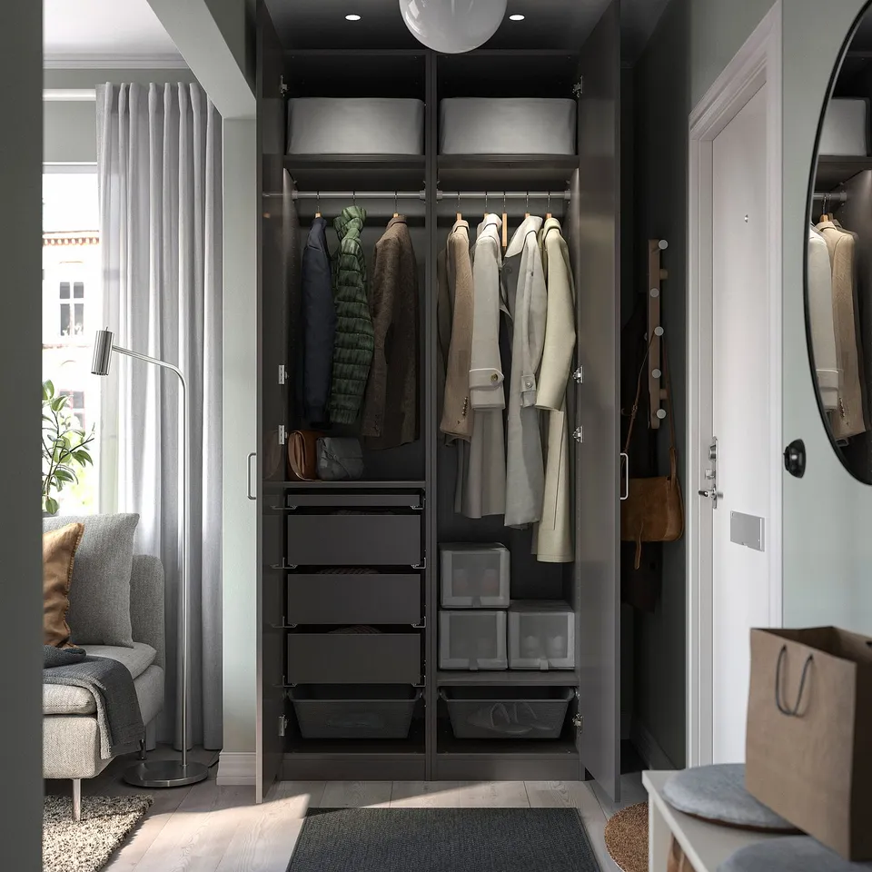 Guardrobe with black PAX wardrobe frame, hanging clothes, drawers, nearby chair & table.