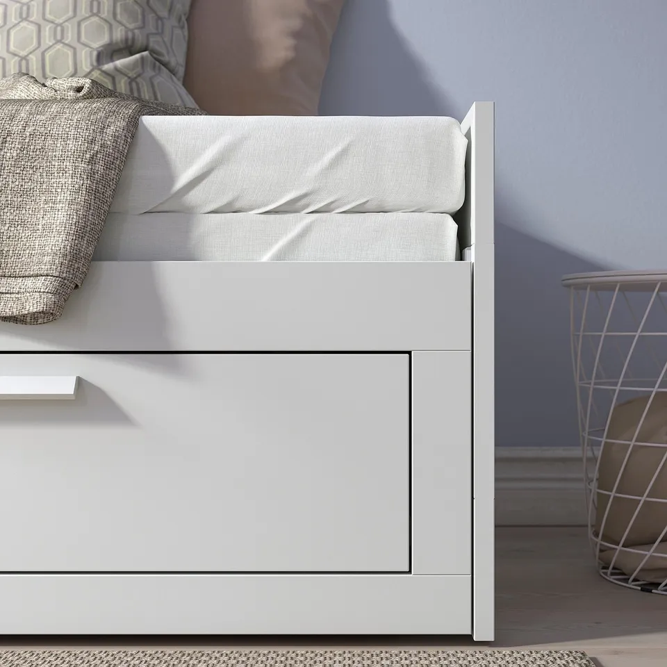 Daybed with storage drawers and white mattress, designed for small spaces, versatile for sleeping and seating.
