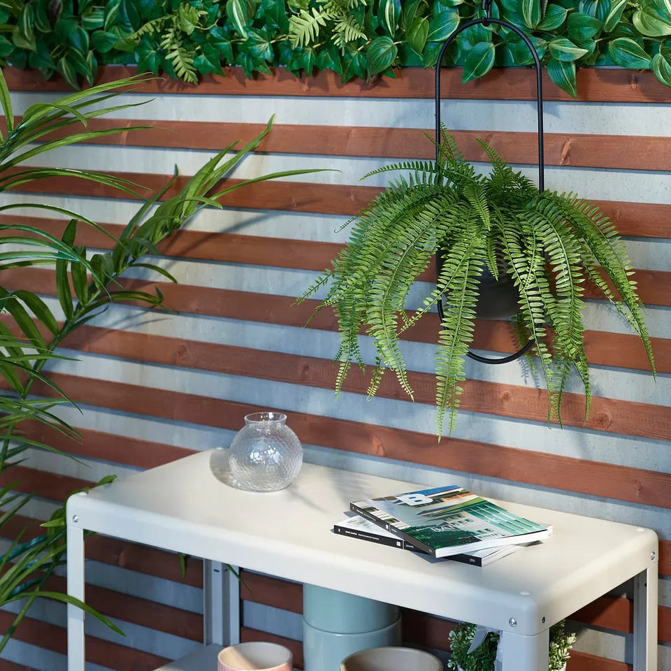 Small table holds books, vase, and potted plant in a cosy space.