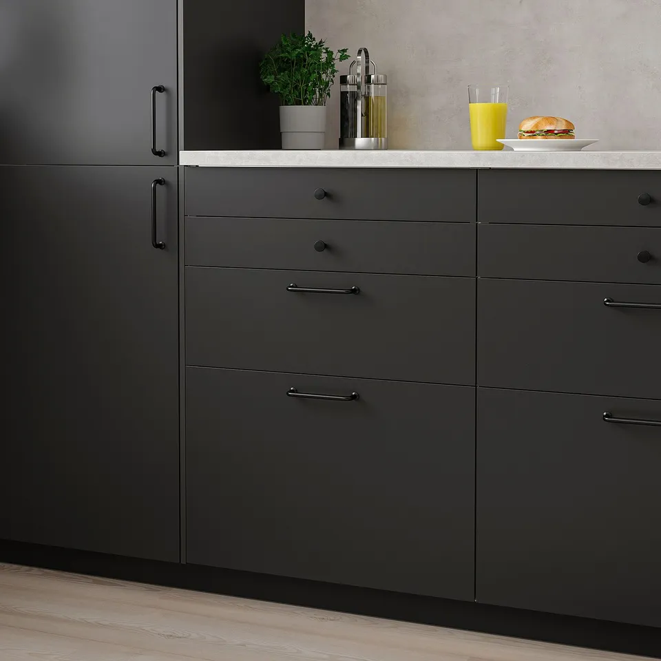 Modern kitchen with dark grey NICKEBO cabinets, smooth black-handled drawers, and a spacious countertop with plants and food.