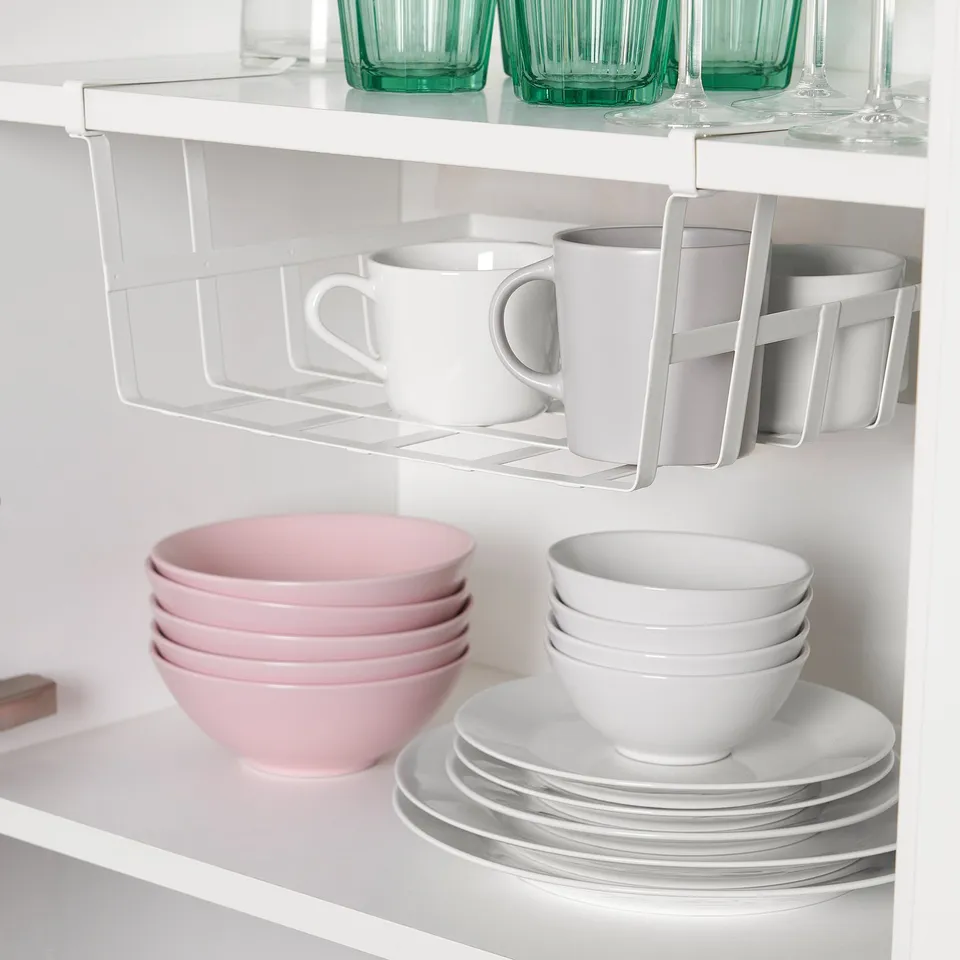 Organised kitchen shelf with hanging mugs and stacked bowls. Green cups on top shelf, white bowls below.