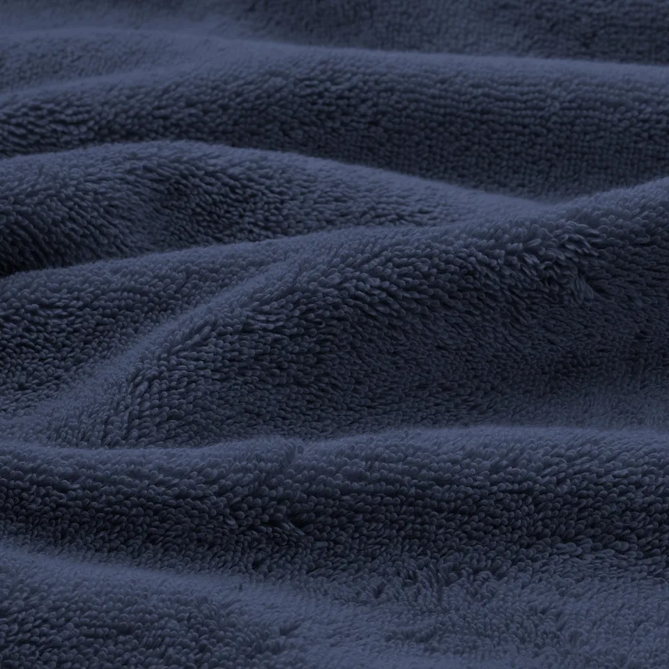 Soft, plush blue towels, neatly folded. Delicate weave, high quality cotton, inviting texture.