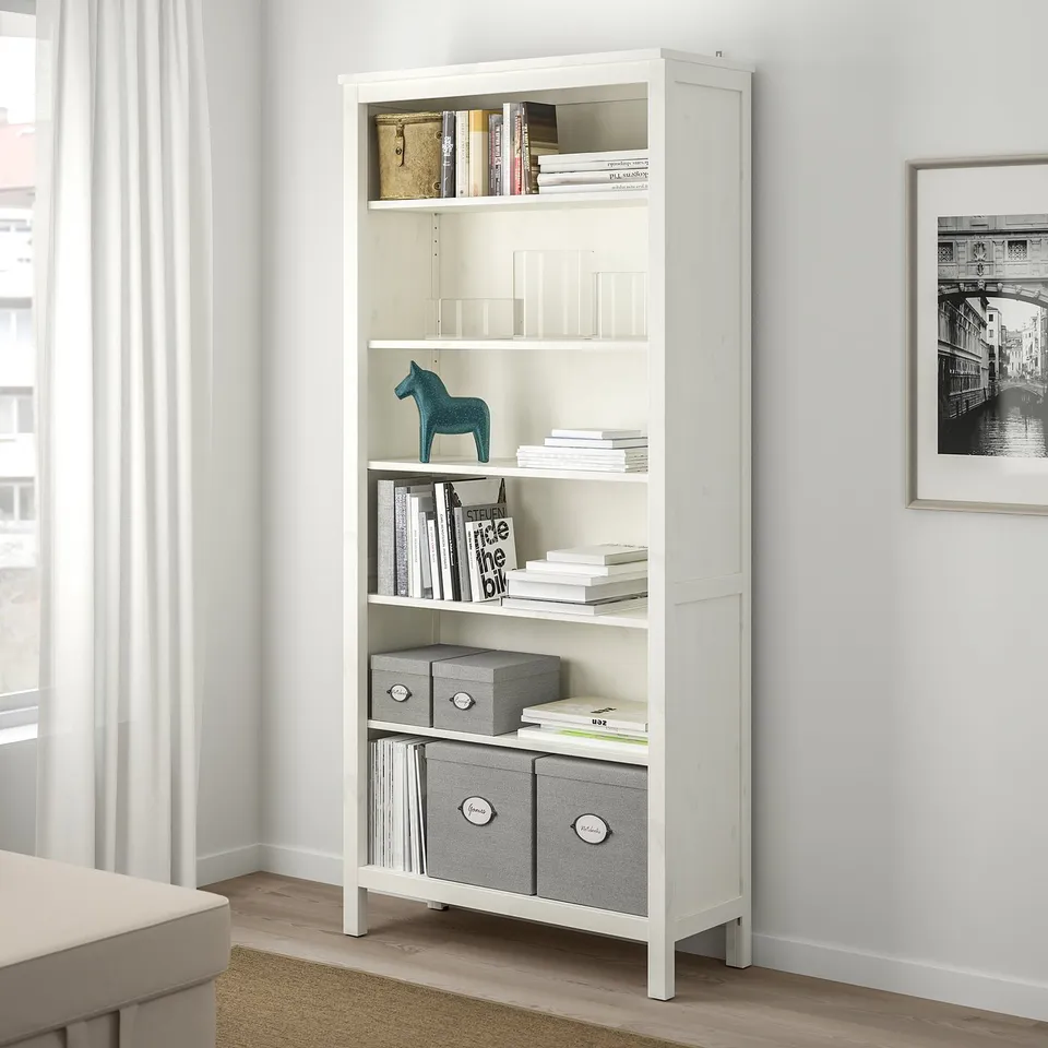 White KVARNVIK bookcase with shelves full of books, decorative items, and storage boxes.