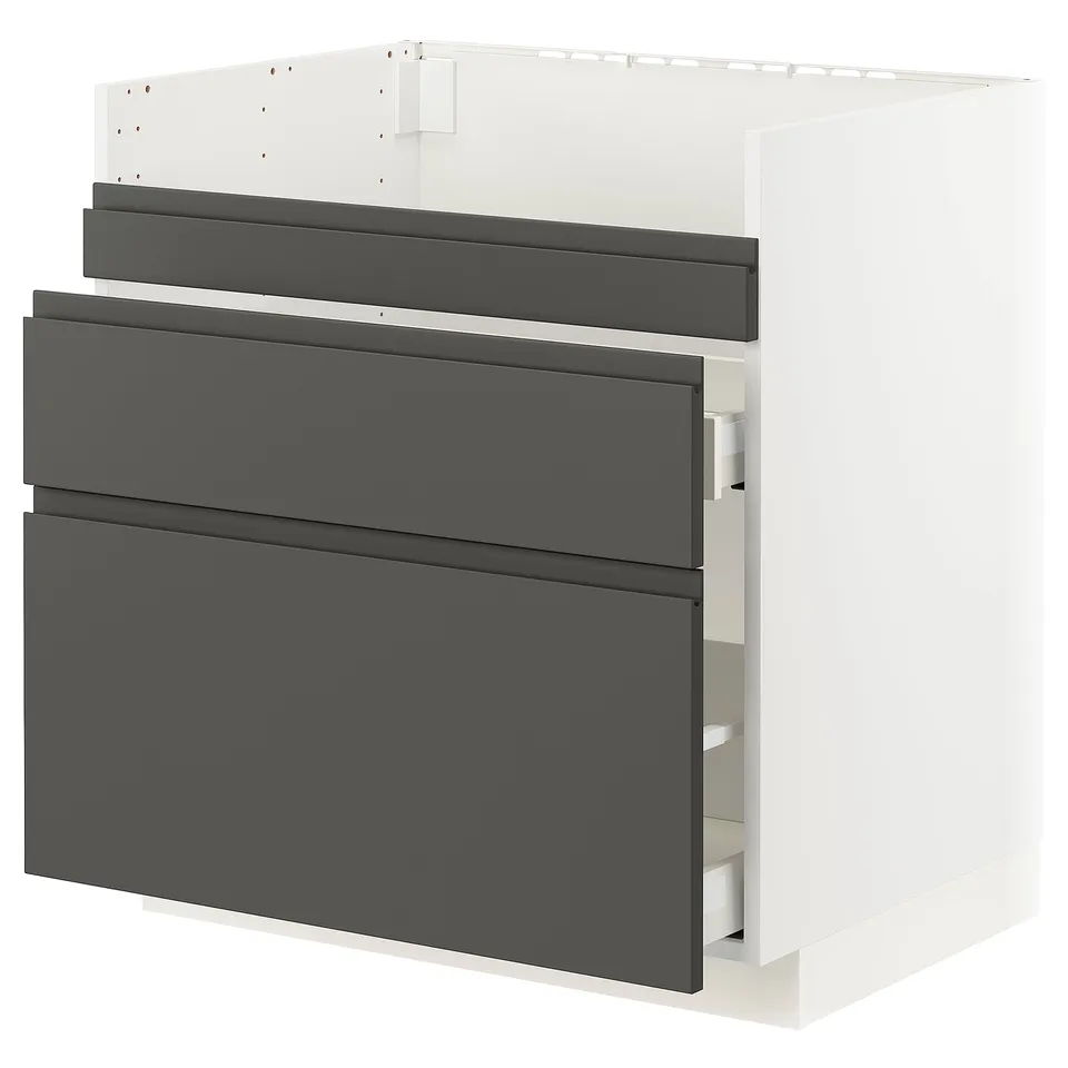 A white METOD kitchen cabinet with dark grey voxtorp drawer fronts. It three drawers and a base for built-in appliances or a sink.
