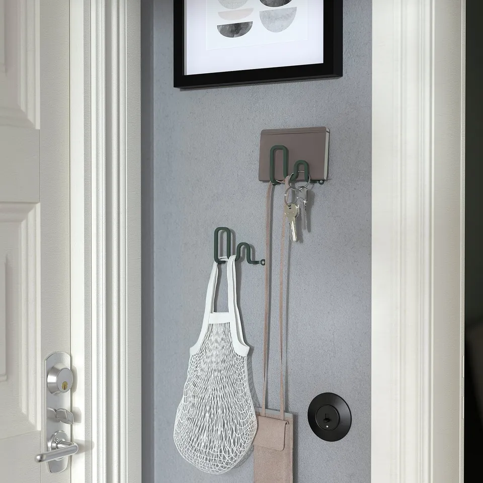 Wall-mounted decorative hook holding keys and a mesh bag.
