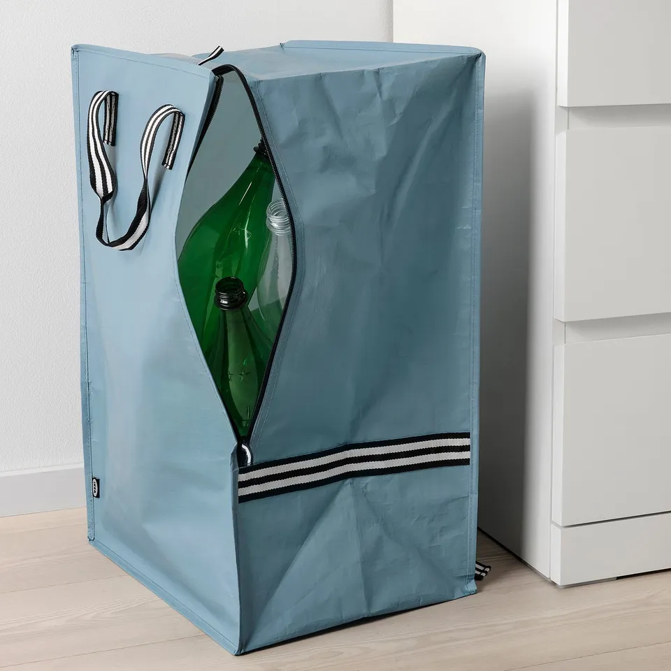 Blue travel bag with stripes, standing. Clear zip shows green bottle inside.