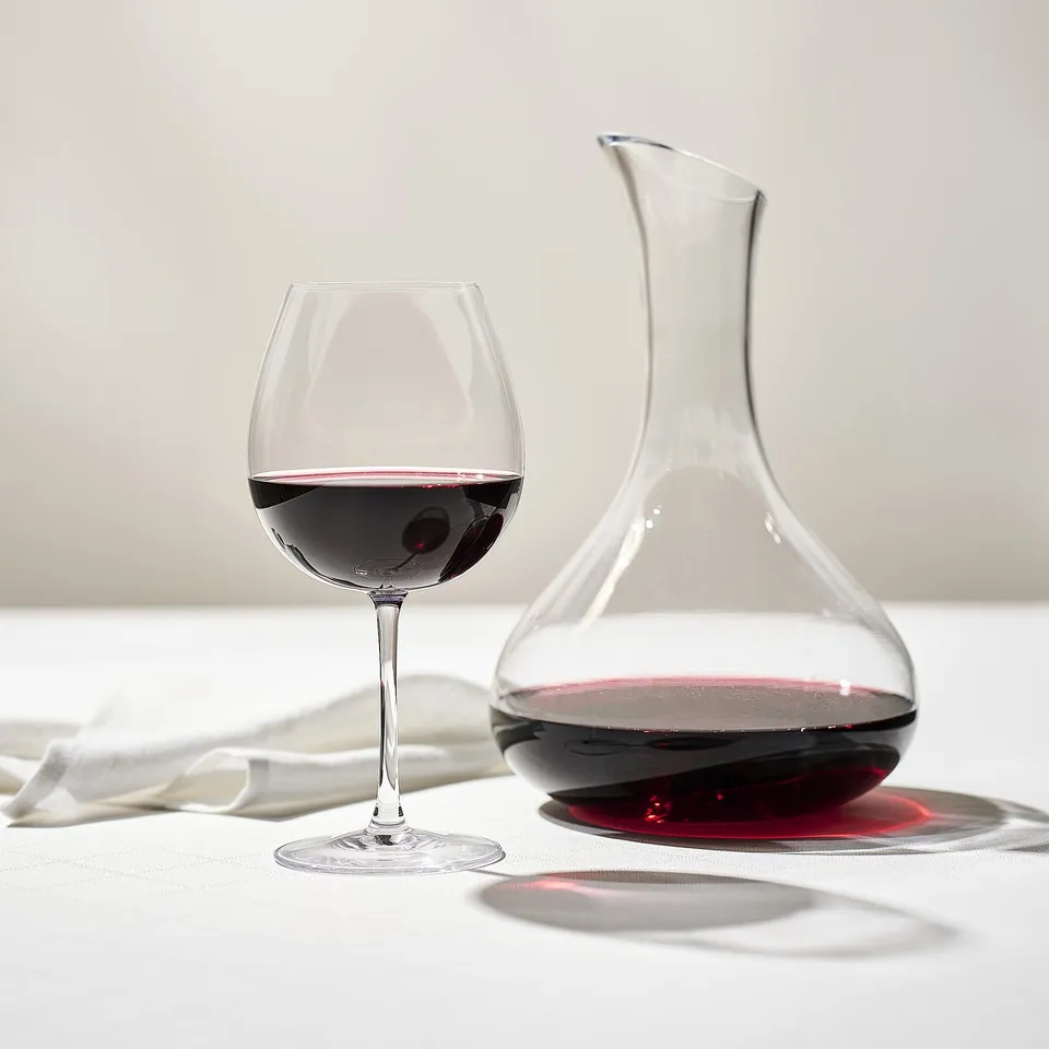 A wine glass and decanter with red wine. The decanter is mouth-blown, and the glass is part of a matching series.