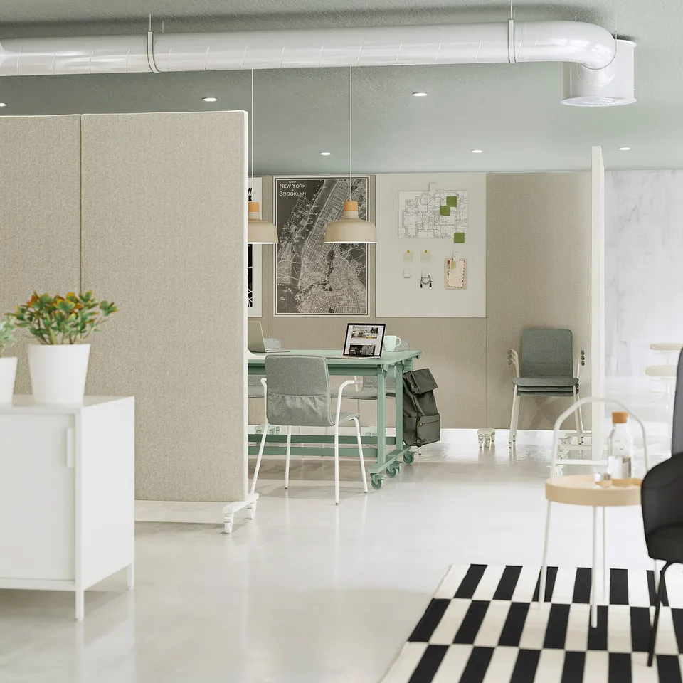 Acoustic screen divider in beige, with wheels, positioned centrally between desks, displaying maps and notes, with a modern office design.