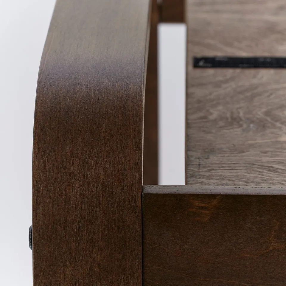 Close-up of poang chairs dark wooden curve; smooth finish, polished surface visible.