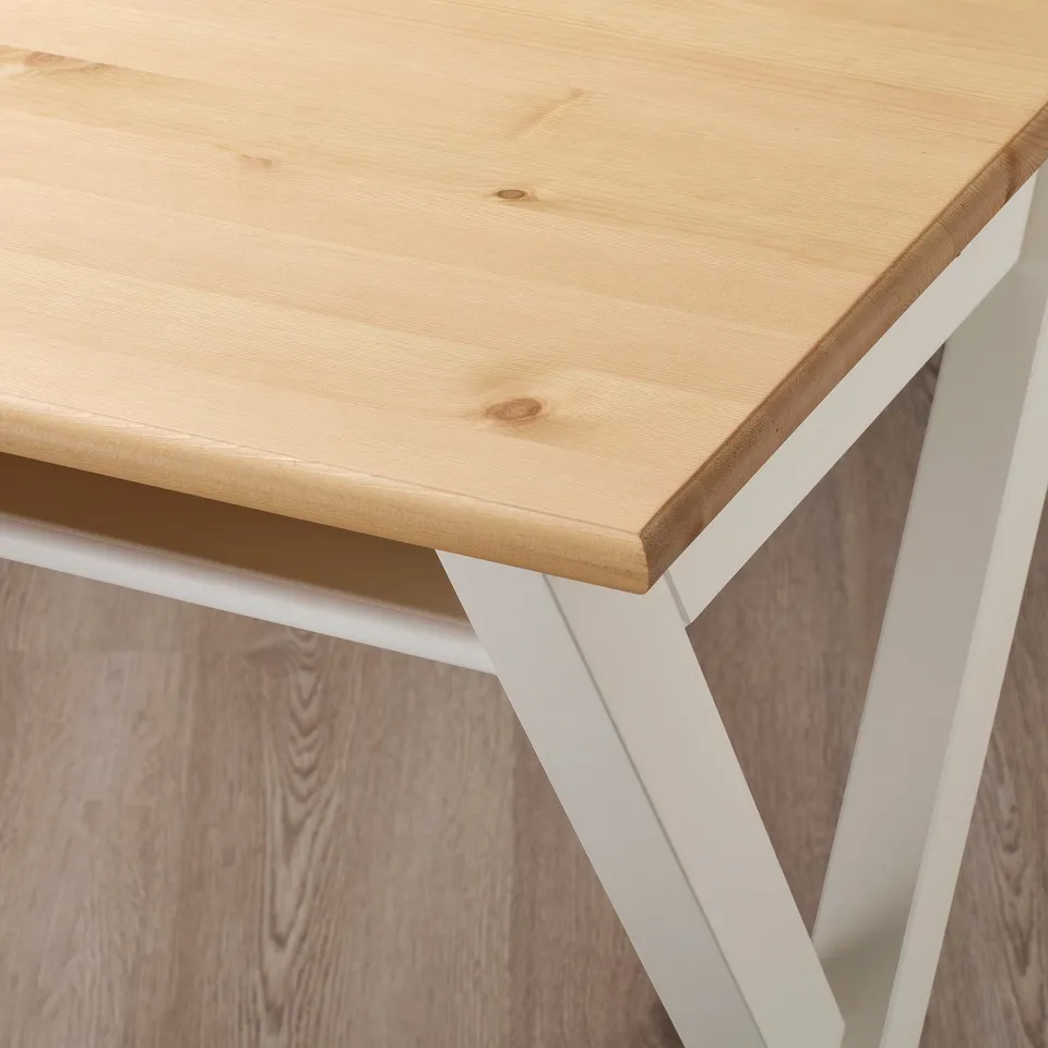 A wooden desk with white metal legs, showing its sturdy construction and clean lines.