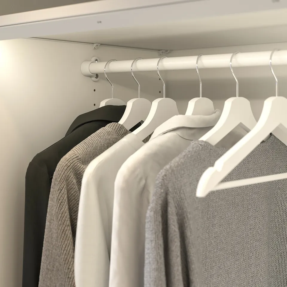 Closet with white KOMPLEMENT rail holding black and grey clothes on hangers.
