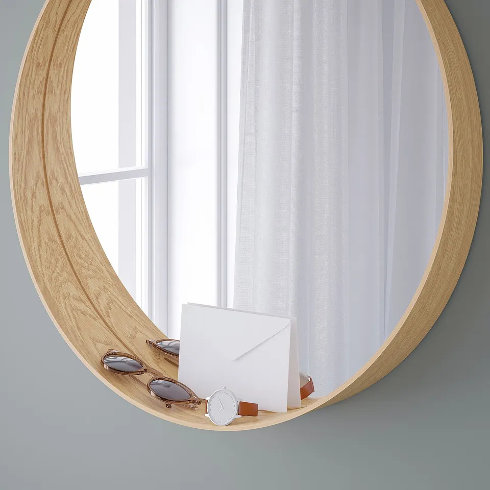 Round wooden-framed mirror with a shelf at the bottom. The shelf holds sunglasses, a watch, and paper. Used for decoration and holding items.