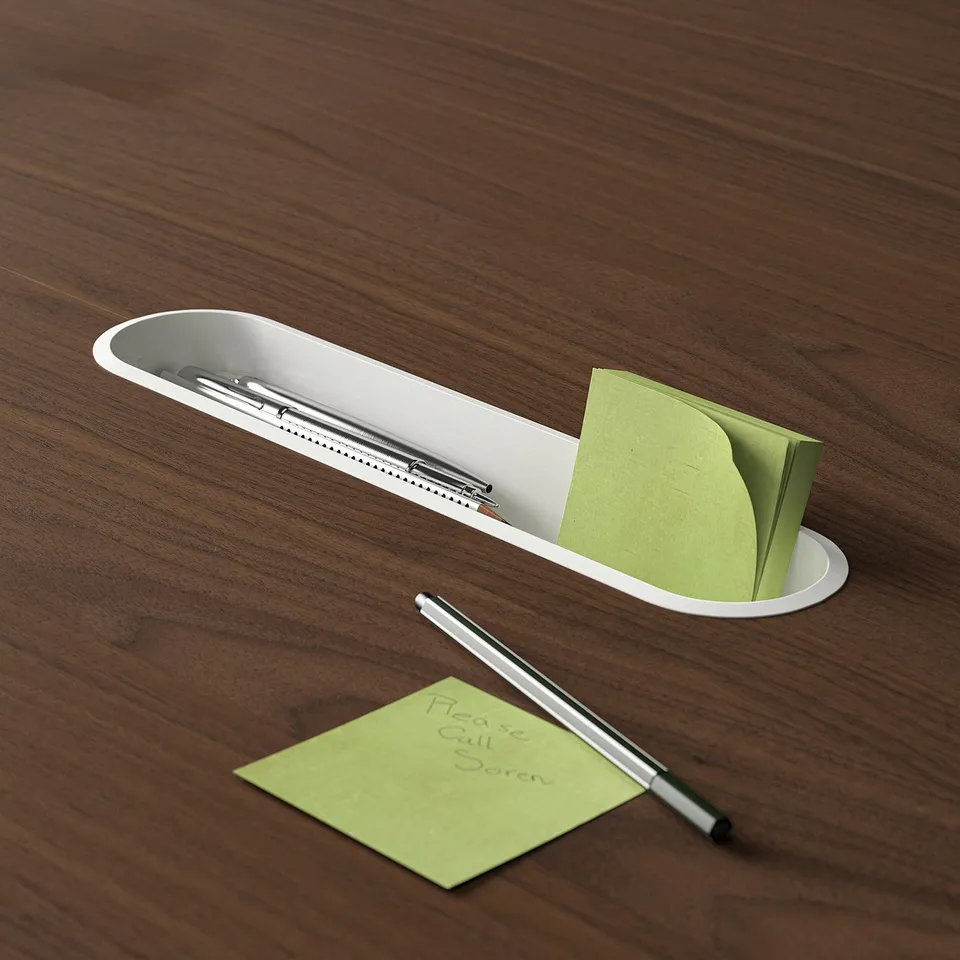 A white oval tray on a wooden table holds pens, a green sticky note, and another note reading please call sven.