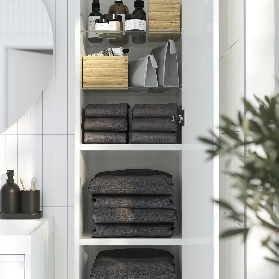 Wall-mounted bathroom cabinet with folded towels and toiletries, utilising vertical space.